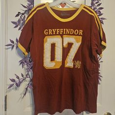 a brown and yellow football jersey hanging on a white door with purple flowers in the background