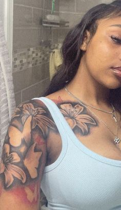 a woman with a flower tattoo on her arm looking at the camera while she brushes her teeth