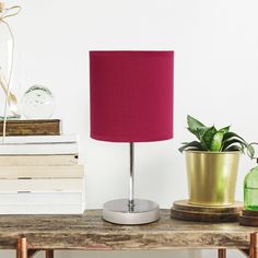 a red lamp sitting on top of a wooden table next to a stack of books