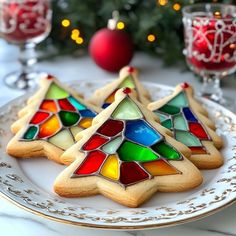 three decorated cookies sitting on top of a white plate next to a christmas tree ornament