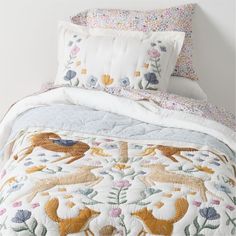 the comforter is made up with many different designs on it, including deers and flowers