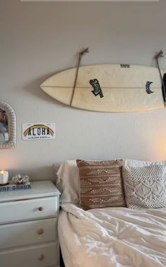 two surfboards hanging on the wall above a bed in a room with white walls