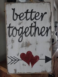 a wooden sign that says, better together with two hearts and an arrow on it