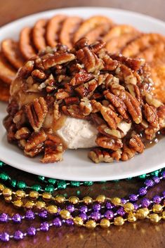 a white plate topped with cookies and pecans next to mardi gras beads