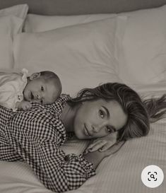 a woman laying on top of a bed holding a baby