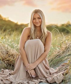 a woman is sitting on the ground with her legs crossed and smiling at the camera