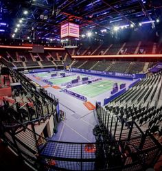 an indoor tennis court is lit up at night with blue and orange lights on the ceiling