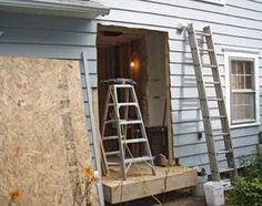 a ladder is in the doorway of a house that's being boarded up with plywood