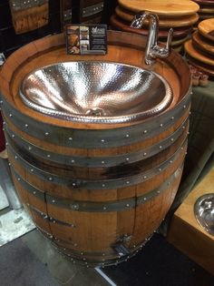 a wooden barrel with a sink in it and some other barrels behind it on display