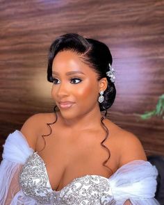 a woman in a white dress posing for the camera with her hair pulled up into a bun