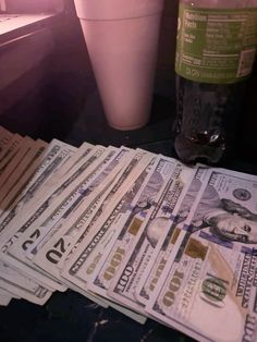 several stacks of twenty dollar bills next to a drink