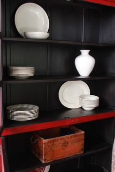 a red bookcase with plates and bowls on it