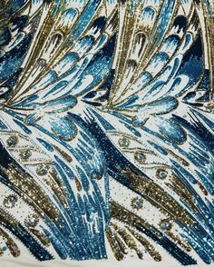 the back side of a blue and gold sequinned dress with feathers on it