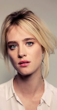 a woman with blonde hair and blue eyes wearing a white shirt looking at the camera