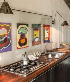 a kitchen with art hanging on the wall above the stove top and sink below it