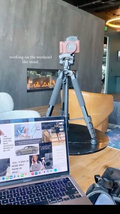 an open laptop computer sitting on top of a wooden table next to a tripod