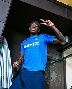 a man standing in front of a building wearing a blue shirt