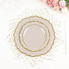 a white and gold plate with flowers on it next to napkins, forks and utensils