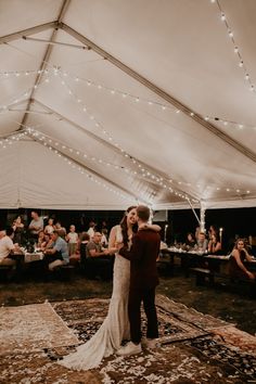 a bride and groom share their first dance under a tent at the end of their wedding reception