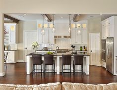 a large kitchen with white cabinets and stainless steel appliances, along with wooden flooring