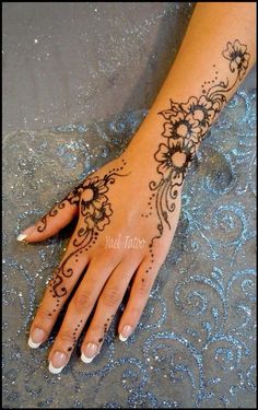 a woman's hand with hennap and flowers on the wrist, which is decorated