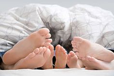 two people with bare feet laying on a bed