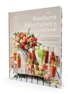 the southern entertainer's cookbook is displayed on a table with flowers in vases