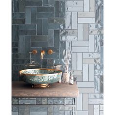 a bowl sink sitting on top of a wooden counter next to a wall covered in tiles