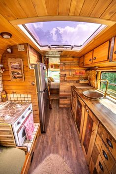 the interior of a tiny home with wood flooring and wooden walls, including an open kitchen area