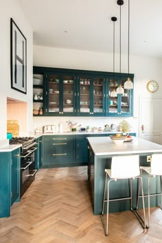 a kitchen with teal cabinets and wooden floors