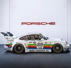 a porsche race car parked in front of a porsche logo