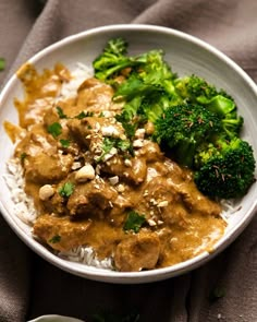 a white bowl filled with rice, meat and broccoli on top of a table