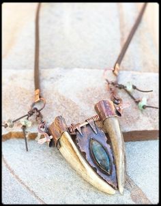 a necklace with an animal's tooth and stone in the center