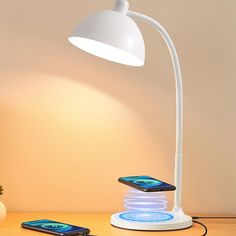 a lamp that is on top of a table next to two cell phone's