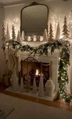 a fireplace decorated for christmas with white lights and greenery on the mantels