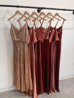 three dresses hanging on a rack in front of a white wall and carpeted floor