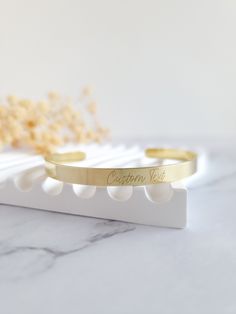 a gold bracelet with the word cotton west engraved on it sitting on a marble surface