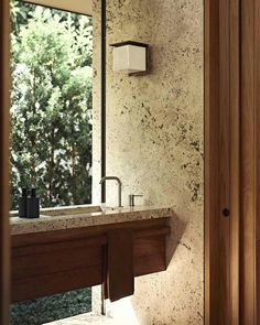 a bathroom sink sitting under a mirror next to a wooden cabinet and counter with soap dispenser on it