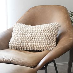 a brown leather chair with a white pillow on it