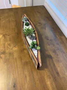 a wooden boat with succulents in it sitting on top of a table