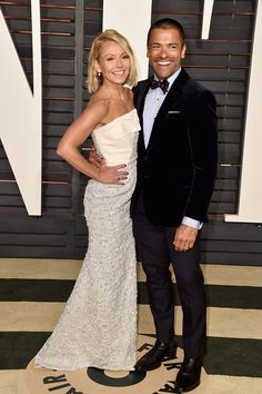 a man and woman standing next to each other in front of a black and white wall