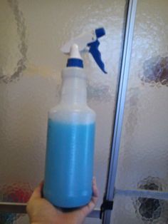 a hand holding a blue and white spray bottle