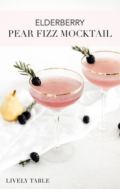 the elderberry pear cocktail is served in coupe glasses and garnished with blackberries