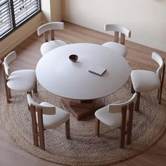 a round table with white chairs and a phone on it in front of a window