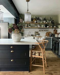 a kitchen with wooden floors and white counter tops, black cabinets and an island in the middle