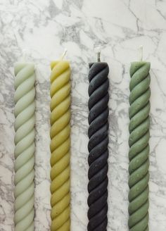 four candles are lined up on a marble surface