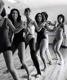 four women in bathing suits are dancing on the floor