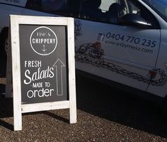 a chalkboard sign in front of a car advertising fresh salads made to order