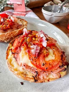 a plate that has some bread on it with tomatoes and other food in the background