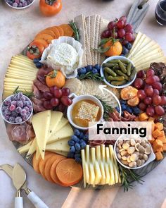 a platter filled with cheese, crackers, grapes, nuts and other foods